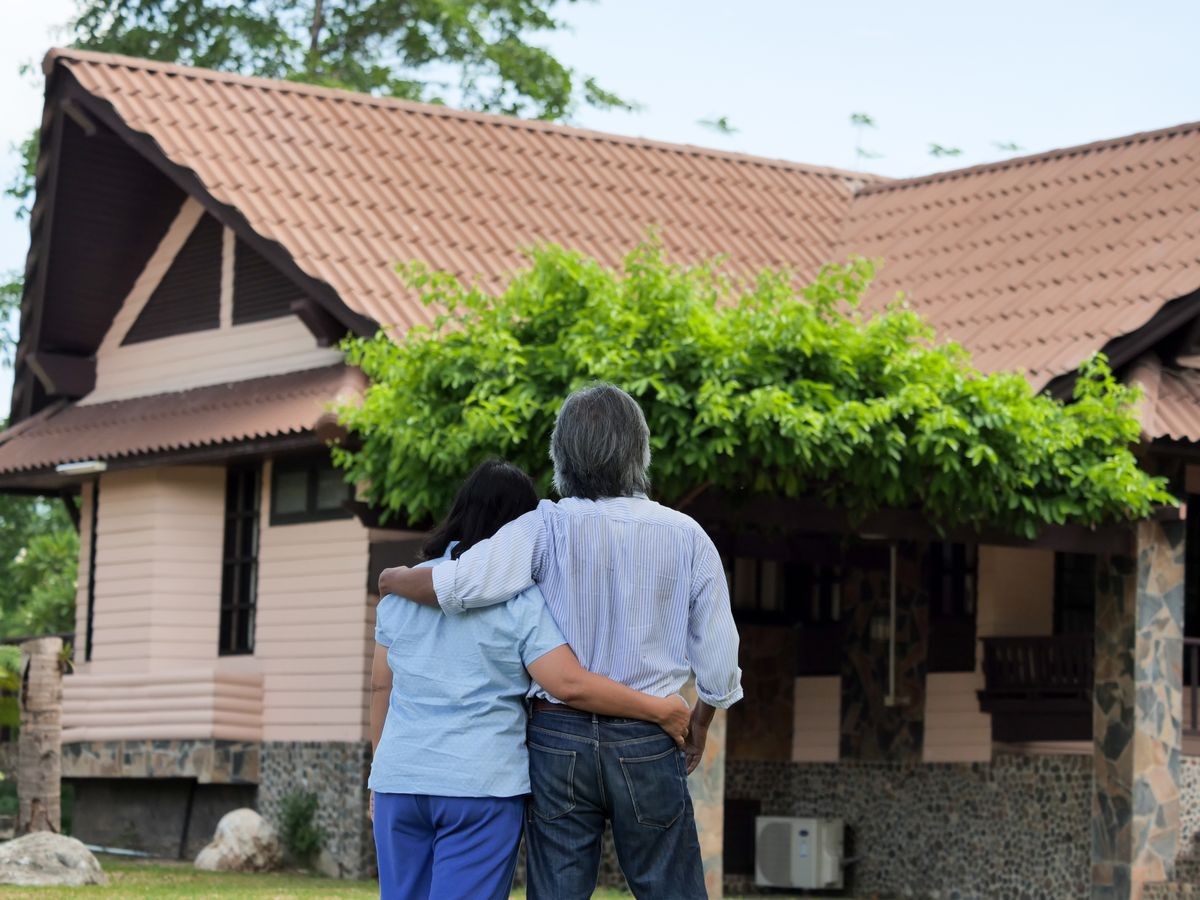 Happy Smiling Asian Elderly Couple Standing in front of New home.